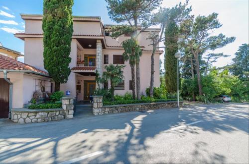 a large house with trees in front of a street at Apartment Zdravka in Crikvenica