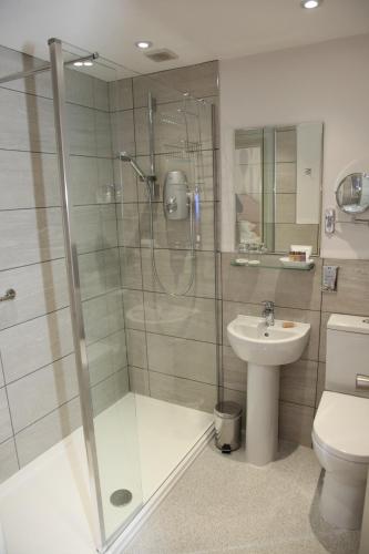a bathroom with a shower and a toilet and a sink at Burt's Hotel in Melrose