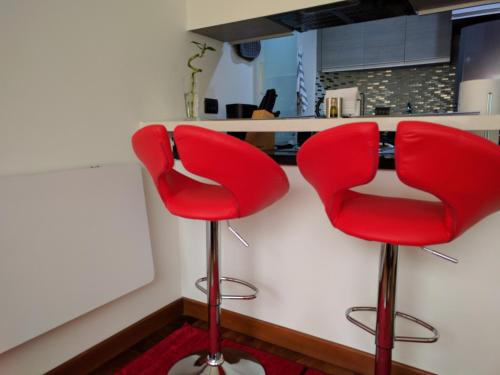 duas cadeiras vermelhas sentadas em frente a um balcão de cozinha em Chic space by Unicentro em Bogotá