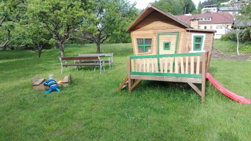 a child playing in the grass next to a play house at Frühstückspension Helmut Koffler in Faak am See