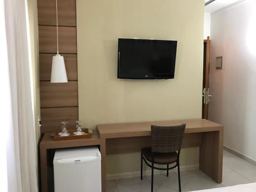 a room with a desk with a television on the wall at Larison Economy by Easy Hotéis in Porto Velho