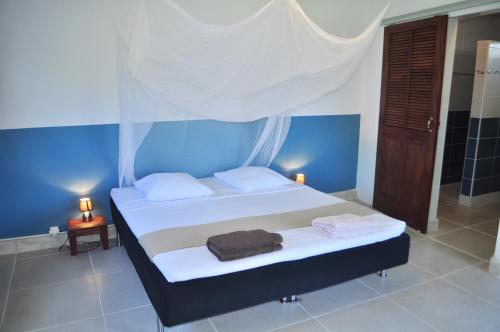 a bedroom with a bed with white sheets and blue walls at Infiniti Blue in Bouillante