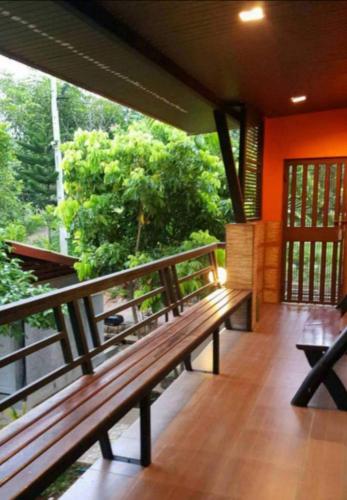 a porch with a wooden bench on a balcony at Kaengkrachan River Hut in Kaeng Krachan