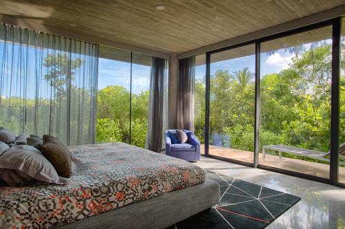 a bedroom with a bed and large glass windows at Villa Islander in Providenciales