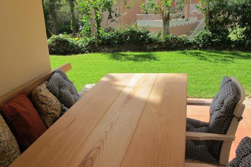 a wooden table and chairs with a table and a yard at Quinta do Lago Golf in Quinta do Lago