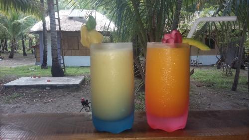 two drinks sitting on top of a wooden table at Sablayan Paraiso Beach Resort in Sablayan