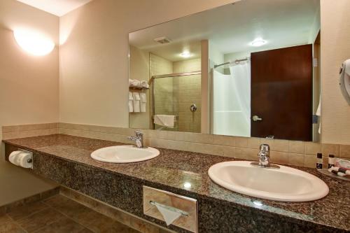 a bathroom with two sinks and a large mirror at Canalta Camrose in Camrose