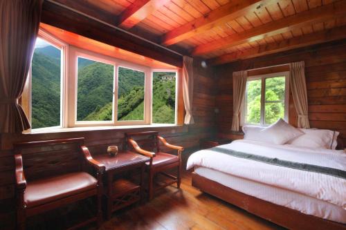 a bedroom with a bed and a desk and windows at La La Shan 5.5KNong Zhuang in Hualing