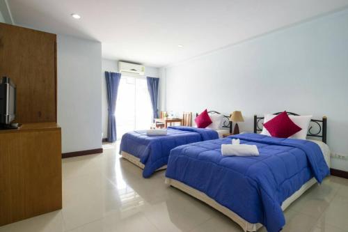 a bedroom with three beds with blue sheets and red pillows at Raya Rawai Place in Rawai Beach