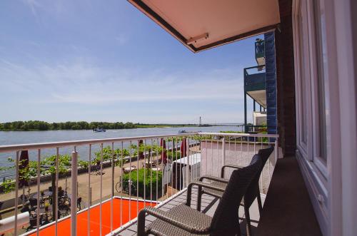a balcony with two chairs and a view of the water at Hotel Rheinpromenade8 in Emmerich