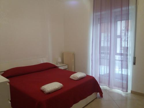 um quarto com uma cama vermelha com duas toalhas em Le cisterne Holiday Home em Manfredonia