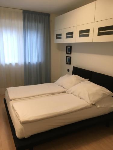 リーヴァ・デル・ガルダにあるAppartamento al Fiumeのベッドルーム1室(白いシーツが備わるベッド2台、窓付)