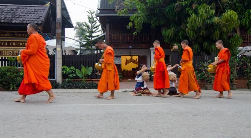 a group of monks in orange robes walking down a street at Villa Chitdara in Luang Prabang