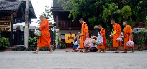 a group of monks in orange robes walking down a street at Villa Chitdara in Luang Prabang