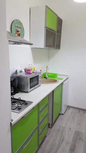 eine Küche mit grünen und weißen Schränken und einer Mikrowelle in der Unterkunft Apart City Center in Braşov