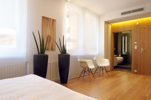 a bedroom with two white chairs and two plants at Hotel Tomášov in Zlín