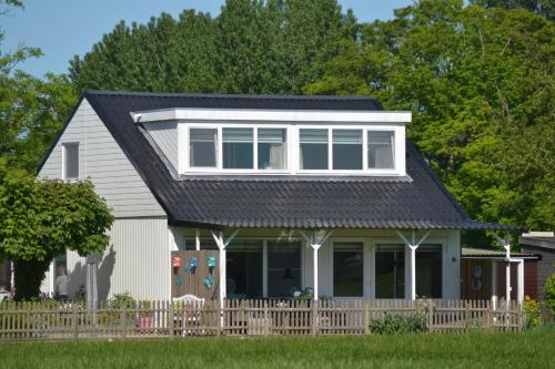 a house with a porch and a fence at Bed & Breakfast Boszicht Leeuwarden in Leeuwarden
