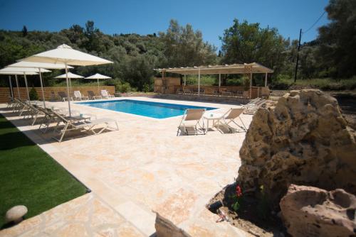 uma piscina com cadeiras e guarda-sóis num quintal em Gea Villas em Lygia