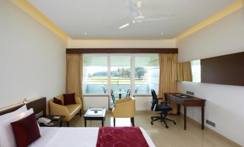 een hotelkamer met een bed, een bureau en stoelen bij RNS Golf Resort & Nature Cure Centre in Māvalli