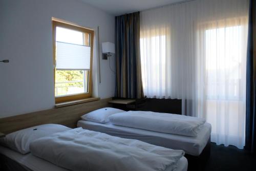 a hotel room with two beds and a window at Blaue Traube in Gebenbach