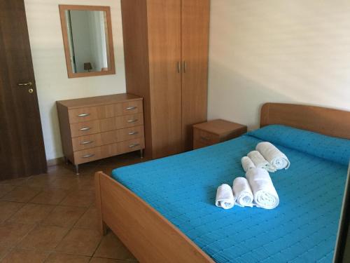 a bedroom with a blue bed with slippers on it at Delta Club Residence in Capo Vaticano