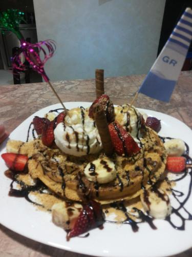 a plate of waffles with strawberries and whipped cream at San Georgio Hotel in Tsoútsouros
