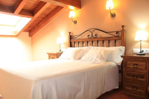 a bedroom with a white bed with a wooden headboard at Apartamentos Los Rosales de Isabel in Corral de Ayllón