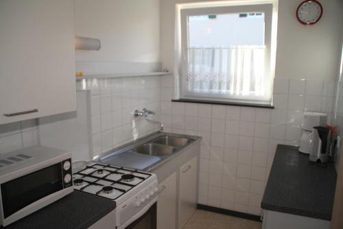 a kitchen with a sink and a stove and a window at Ferienanlage Seehof in Krumpendorf am Wörthersee