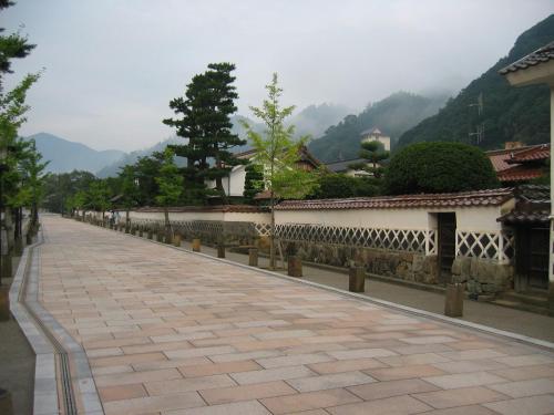 a walkway next to a wall with mountains in the background at Noren Yado Meigetsu in Tsuwano