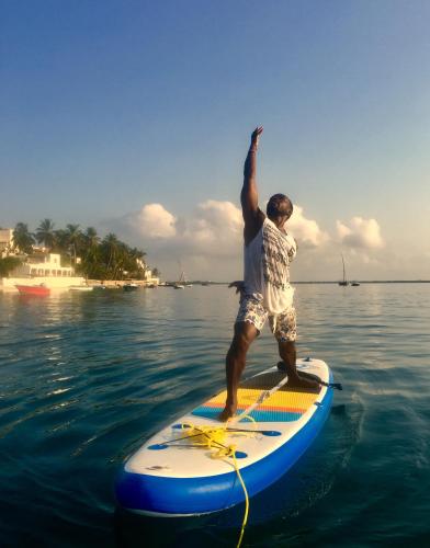a man standing on a surfboard in the water at Msafini Hotel in Lamu