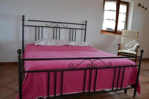 uma cama com um cobertor rosa e uma cadeira num quarto em Dammuso Primavera em Pantelleria
