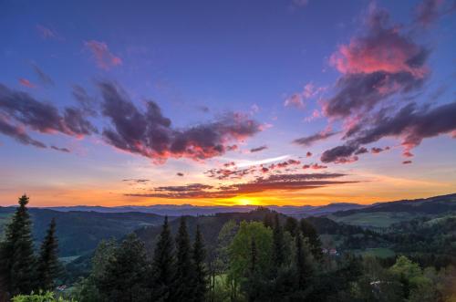 a sunset in the mountains with trees in the foreground at Biolandhaus Arche in Eberstein