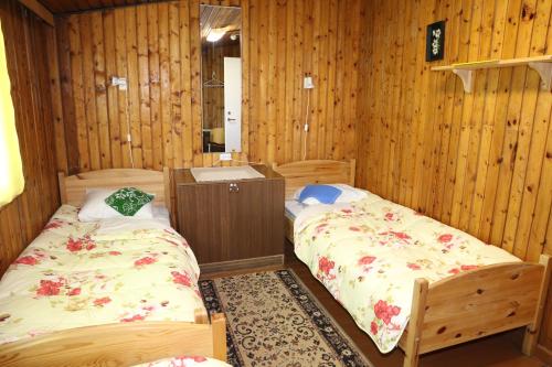Dos camas en una habitación con paredes de madera. en Mihkli Guest House, en Haapsalu