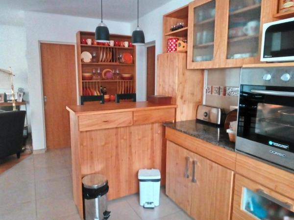 cocina con armarios de madera y encimera negra en La casa de Silvia en Puerto Madryn