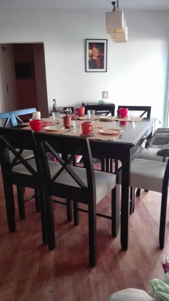 una mesa de comedor y sillas con cuencos rojos. en La casa de Silvia en Puerto Madryn