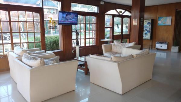 sala de estar con 2 sofás blancos y TV en San Remo Palace Hotel en Villa Gesell