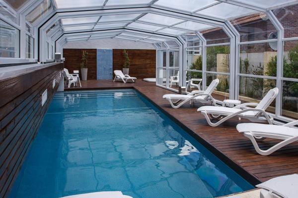 una piscina con sillas blancas en Hosteria Chaltu en Villa Gesell