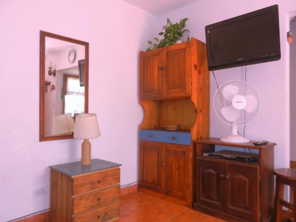 sala de estar con TV, armario y espejo en Complejo El Bosque en Villa Gesell