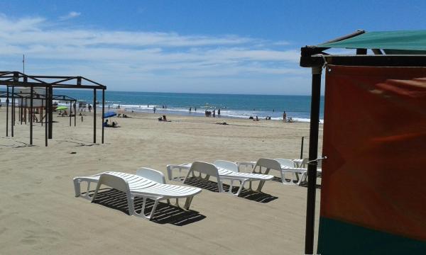 una playa con sillas y una estructura de juegos y el océano en Playa 1 en Villa Gesell