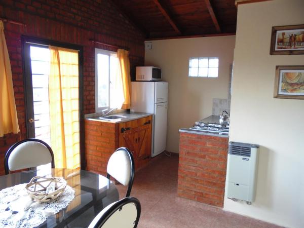 una pequeña cocina con mesa y refrigerador en Cabañas Doña Itati, en Villa Carlos Paz