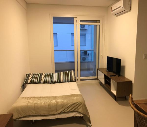 a bedroom with a bed and a tv and a window at Apto Praia Ingleses 3q 2g in Florianópolis