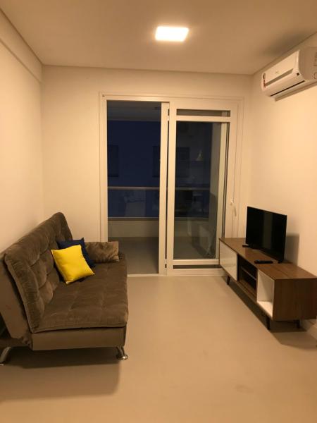 a living room with a couch and a television at Apto Praia Ingleses 3q 2g in Florianópolis