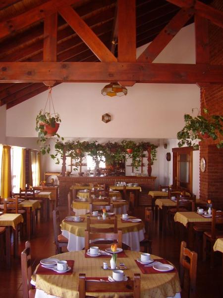 comedor con mesas y sillas de madera en Hostería Santa Bárbara en Villa Gesell