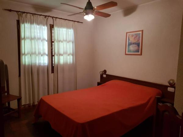 1 dormitorio con cama roja y ventilador de techo en Apart Santander, en Mina Clavero