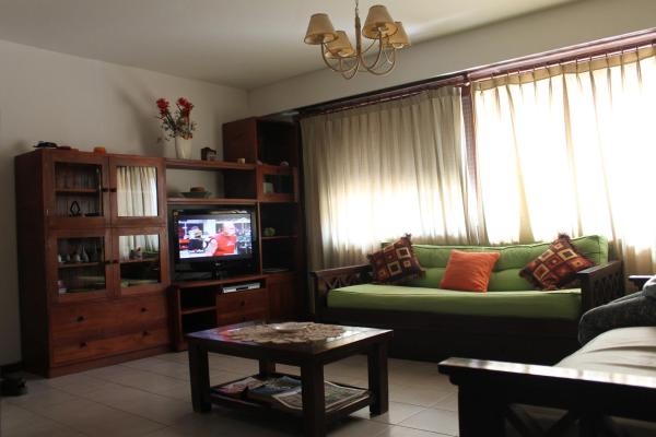 sala de estar con sofá verde y TV en Posta Del Cocodrilo en Pinamar