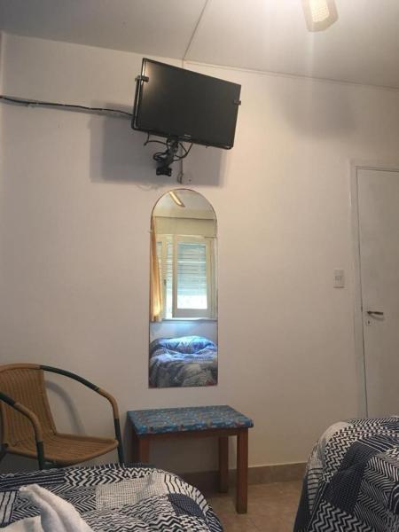 1 dormitorio con espejo, 1 cama y 1 silla en Bariloche en Villa Gesell