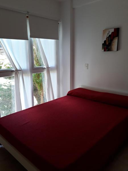 1 dormitorio con cama roja frente a una ventana a Familiar Pinar Gesell en Villa Gesell