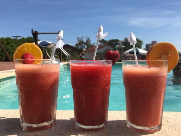 tres bebidas sentadas en una mesa junto a una piscina en el Hotel Don Carlos en Villa Gesell