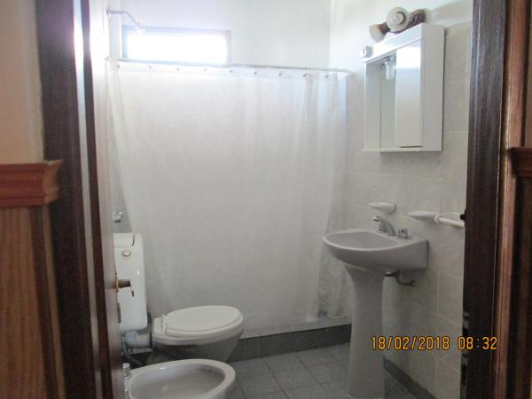Baño blanco con aseo y lavamanos en Edificio Sole Mio en Villa Gesell