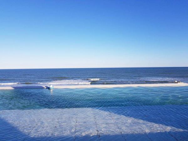 una piscina de agua con una playa de fondo en Los Pinos Pinamar en Pinamar